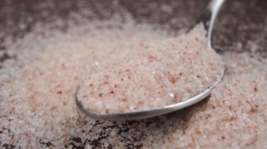 Bir çay kaşığını Himalaya tuzuyla ağır çekimde doldurun. Makro atış. Pudra pembesi.