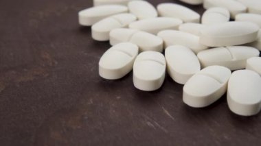 Koyu kahverengi panoda beyaz tıbbi haplar. Makro. Doli Vuruşu