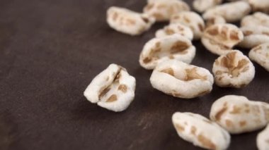 Koyu ahşap arka planda büyülenmiş buğday kabartması. Pişmemiş mısır gevreği. Makro. Dolly vurdu.