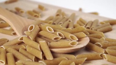 Çiğ İtalyan penne makarnasını doli hareketli tahta bir kaşığa bırak. Makro atış. Yavaş çekim