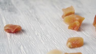 Kurutulmuş papaya meyvesi. Ağır çekimde tahta bir yüzeye düşen küpler. Dolly vurdu. Makro. Tropik egzotik tatlı.