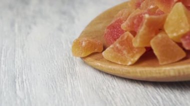 Kesilmiş kurutulmuş papaya meyvesi, tahta kaşıktan yavaş çekimde düşer. Makro. Doli Vuruşu