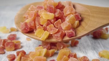 Kurutulmuş meyveli papaya atıştırmalıkları tahta kaşıktan tahtaya yavaş çekimde düşer. Makro atış. Vitaminli tropik tatlı yakın plan.