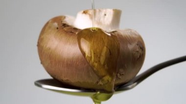 Pişmemiş kahverengi şampiyon mantarı yavaş çekimde sebze yağıyla doldurulur. Makro atış. Yakından su sıçrat. Metal bir kaşıkta