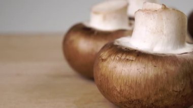 Pişmemiş çiğ şampiyon mantarları ve kesme tahtasının üzerinde kahverengi şapkalar. Makro. Doli Vuruşu