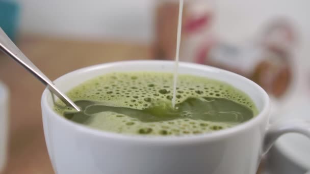 Leite Derramado Uma Xícara Branca Cheia Com Chá Matcha Espumoso — Vídeo de Stock