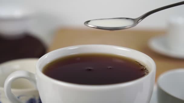 将新鲜牛奶倒入茶匙 倒入一杯浓郁的红茶中 用慢动作泼洒和滴落 白色和深褐色特写的对比 — 图库视频影像