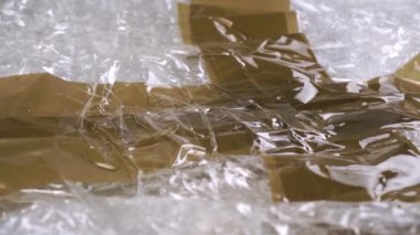 Baloncuk ambalajında yapıştırıcı bant. Buruşmuş plastik yüzey. Teslimat konsepti. Makro. Dolly vurdu.