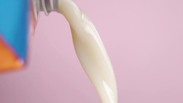 スローモーションでパックから野菜のオートミルクを入れてください マクロショット ピンク色の背景に 乳糖を含まない代替栄養製品 — ストック動画