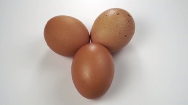 Bir el, yeşil koruyucu tıbbi maskeyle üç kahverengi tavuk yumurtasını kaplıyor. Salmonella ve coronavirus koruma konsepti