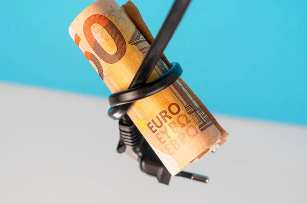 Euro bank note tied in a knot with an electric cable with a plug on a blue white background. Green alternative energy and electricity cost savings concept