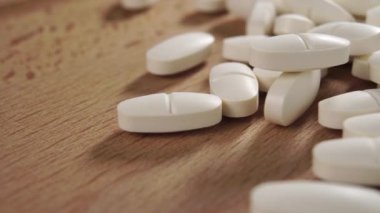Ahşap bir yüzeye yığılmış bir yığın beyaz oval ilaç. Makro. Doli Vuruşu