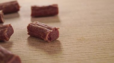 Kedi maması parçaları. Yakından. Ahşap bir yüzeyde kurutulmuş et çubukları. Makro. Doli Vuruşu