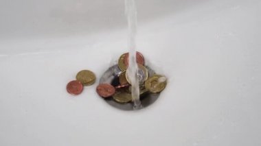 Avro sentlik sikkeler yavaş çekimde bir su akıntısının altında beyaz bir lavaboda. Para aklama ve fatura konsepti