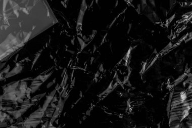 Siyah, buruşuk, siyah plastik kaplama. Soyut koyu arkaplan. Buruşmuş plastik ambalaj