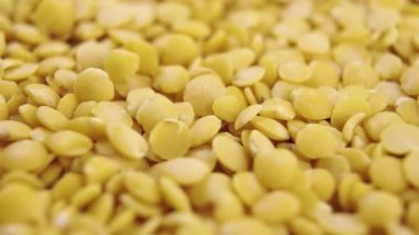 Pişmemiş sarı mercimekler yavaş çekimde yığılırlar. Makro atış. Döndürme. Çiğ baklagiller