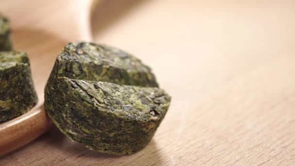 植物药丸放在木板表面的木制勺子上 药丸中的干绿茶叶 替代自然医学的概念 Dolly Shot — 图库视频影像
