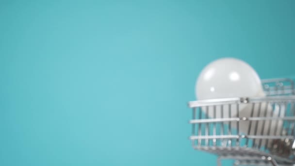 Энергосберегающая Лампочка Мини Корзине Супермаркета Цветном Синем Фоне Эффективность Энергосберегающая — стоковое видео
