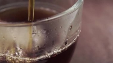 Köpüklü ve buharlı taze siyah çay. Ağır çekimde sıçrıyor. Tahta kahverengi masa. Aromatik sağlıklı içecek konsepti