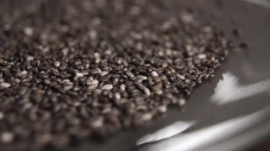 Chia tohumları parlak bir fincan tabağına ağır çekimde düşer. Makro. Döndürme. Salvia Hispanica 'da. Sağlıklı gıda konsepti