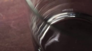 Donmuş buz küpleri, ahşap bar tezgahında yavaş çekimde boş bir bardağa düşer. Makro atış. Döndürme. Tazeleyici kavram