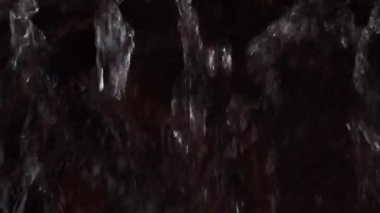 Koyu ahşap bir yüzeye akan bir su akıntısı. Ağır çekimde sıçrıyor. Yakın plan.
