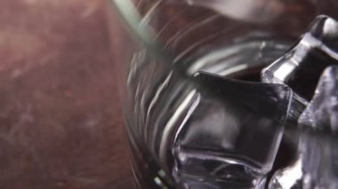 Tahta kahverengi bir yüzey üzerinde boş dönen bir bardakta taze buz küpleri. Makro. Soğutma ve tazelik kavramı