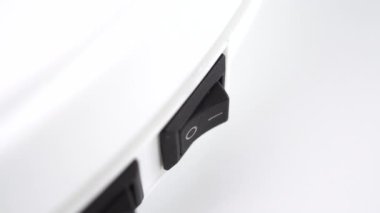 Üzerinde siyah plastik bir düğme olan beyaz elektrikli aletin düğmesine basmak. Enerji tasarrufu kavramı