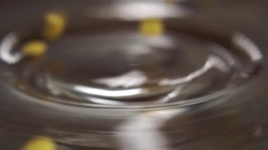 Pişmemiş sarı mercimek yavaş çekimde dönen parlak bir tabağa düşer. Makro. Çiğ baklagiller