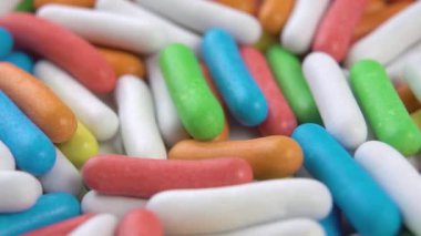 Çok renkli Dragee şekerlemeleri. Ağır çekimde düşüyorum. Parlak jöleli renkli bir doğum günü tatlısı. Makro. Döndürme