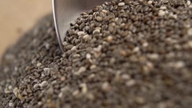 Son derece yakın planda bir yığın chia tohumunun içinde kaşık taşımak. Makro. Yavaş çekim