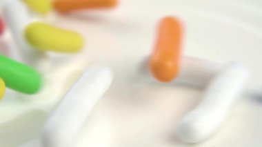 Rengarenk jöleli renkli tatlılar beyaz bir tabağa saçılmıştır. Çeşitli parlak renkler. Dikdörtgen şekilli. Makro. Yavaş çekim