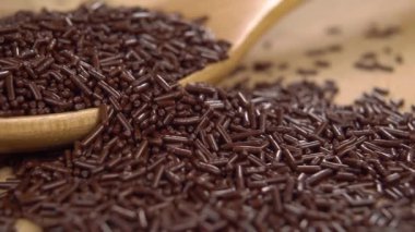 Ahşap bir yüzeye serpiştirilmiş bir kaşık dolusu çikolata. Makro. Doli Vuruşu