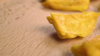Dried mango slice on a wooden textured board. Macro. Dolly shot.
