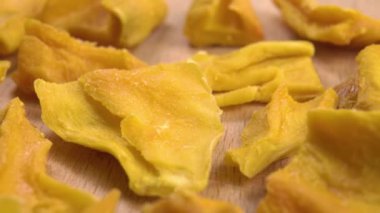 Heap of dried exotic mango fruit slices on a wooden surface. Macro. Dolly shot. Vitamin snack