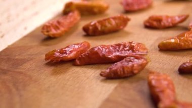 Dried red hot cayenne piripiri peppers falling onto a wooden surface in slow motion. Macro. Dolly shot.