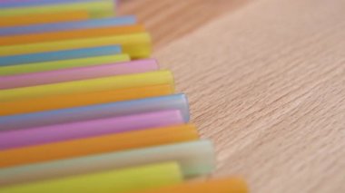 Colored colorful drinking plastic straws on a wooden surface. Material recycling concept. Macro. Dolly Shot