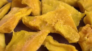 Dried preserved mango pieces. Macro. Rotation