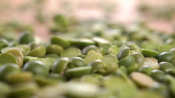 乾燥した緑の分割エンドウ豆はゆっくりとした動きで木製の表面のヒープに落ちます マクロショット 生の未調理マメ科豆 — ストック動画
