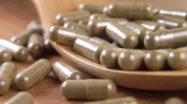 Bitkisel gıda takviyeli tıbbi kapsüller. Tahta bir kaşığa yığılıp düşmek. Kırsal tarzda. Makro. Ağır çekim. Alternatif doğal tıp konsepti