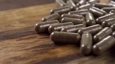 Esrar bitkisel gıda destek kapsülleri koyu ahşap bir yüzey üzerinde. Makro. Doli Vuruşu