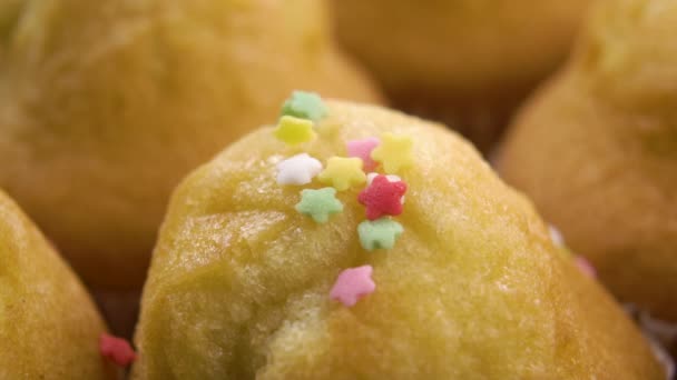 砂糖の装飾的なカラフルな休日の星のスプリンクル焼きカップケーキ スローモーションで甘いベーキング装飾を落下 マクロショット — ストック動画