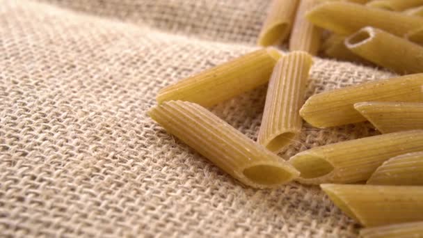 Bio Vollkorn Braune Ungekochte Penne Nudeln Auf Texturiertem Vintage Burlap — Stockvideo