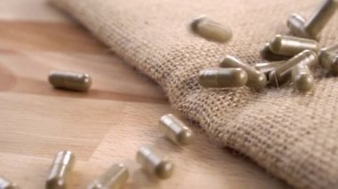 Tıbbî kapsülleri kaba bir çuval bezi ve ahşap bir yüzeye düşürmek. Ağır çekim. Makro