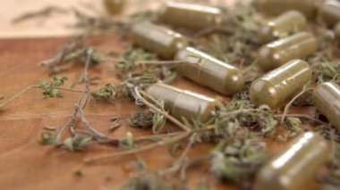 Ahşap bir yüzeyde tıbbi kapsüllü kurutulmuş şifalı bitki. Makro. Dolly vurdu. Bitkisel tıp konsepti