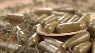 Ahşap bir yüzey üzerinde kurumuş şifalı bitkilerle dolu tıbbi kapsüller. Makro. Dolly vurdu. Bitkisel tıp konsepti