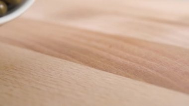 Ağır çekimde beyaz bir bardaktan tıbbi kapsülleri tahta bir yüzeye fırlatmak. Bitkisel tıp konsepti. Makro çekim