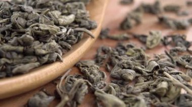 Geleneksel kuru yeşil çay yapraklarıyla dolu bir tahta kaşık. Makro. Dolly vurdu. Rustik biçim görünümü