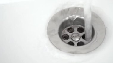 Beyaz bir lavaboda içme suyu akıntısı. Ağır çekim. Yakın plan..