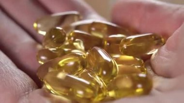 Avucunun içinde balık somonu yağı ve kuru buruşuk derili sarı tıbbi kapsüller. Omega-3 hapları. Makro